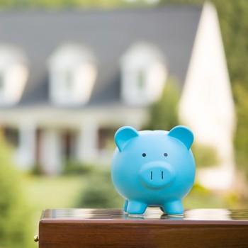 A piggy bank in front of a dream house.