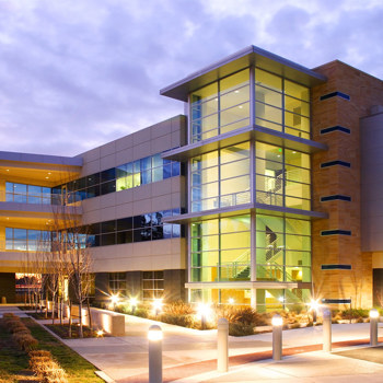 A modern office building lit up from inside at dusk