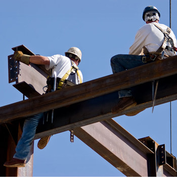 Steel workers placing beams on a high building