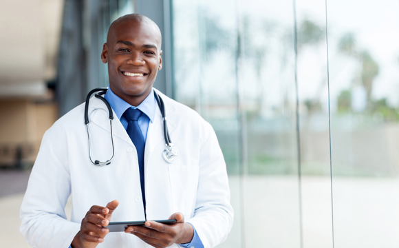 A smiling young doctor in a windowed hospital corridor