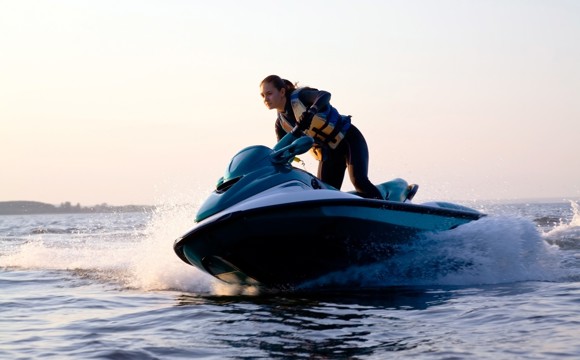 A women driving a personal watercraft on a lake.