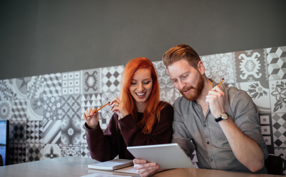 A couple on a couch with a tablet - excited at their budget
