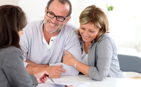 A woman explaining a document to a married couple.