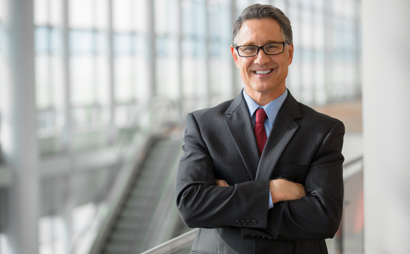 A smiling professional in a suit with arms folded