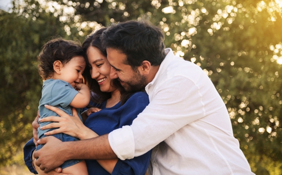 A couple holding their child together.