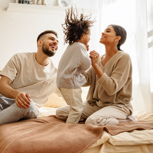 Family with kid jumping on the bed
